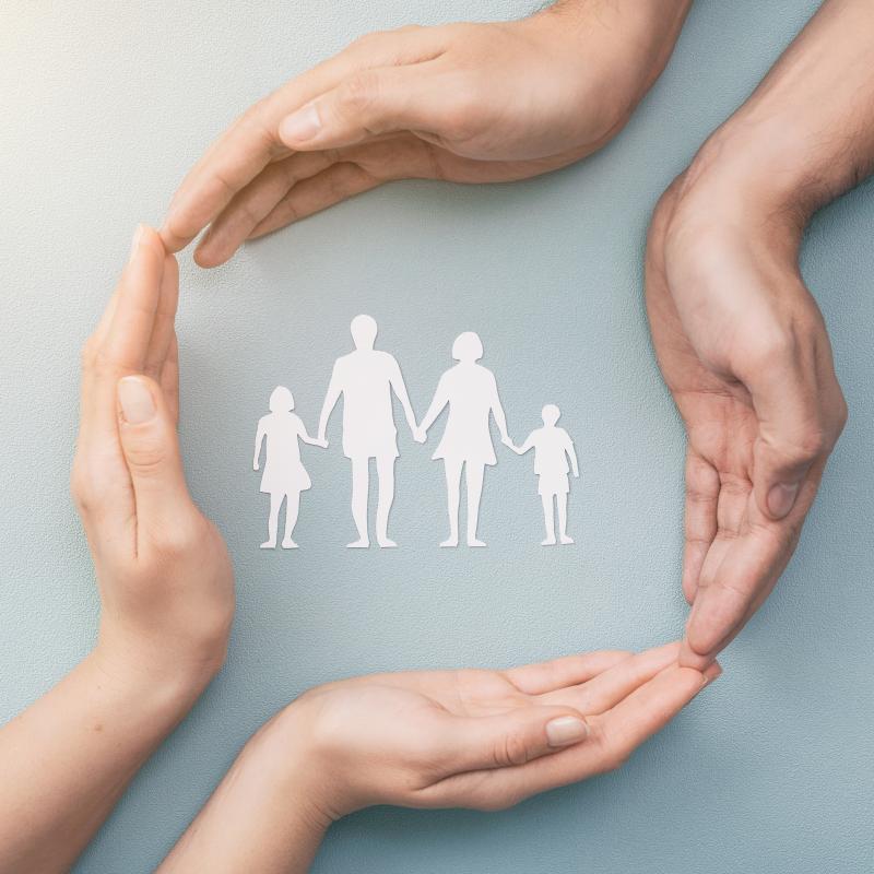 Family care concept. Hands with paper silhouette on table.