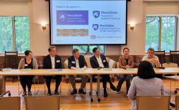 Group of panelists sits at the front for a discussion about research and collaboration.
