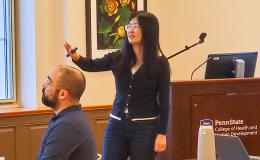 Xue Zhang, an Asian woman wearing a dark sweater, presents to the group. 