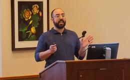 Nelson Roque, a white man wearing a blue shirt with a beard, presents to the group.
