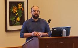 Nelson Roque, a white man wearing a blue shirt with a beard, presents to the group.