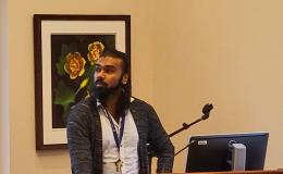Mohanraj Krishnan, a faculty member wearing a long cardigan and white button-up, presents to the group.