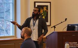 Mohanraj Krishnan, a faculty member wearing a long cardigan and white button-up, presents to the group.