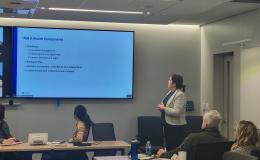 Cheryl Thompson, a woman wearing a white jacket, speaks to the group about NIH K awards.