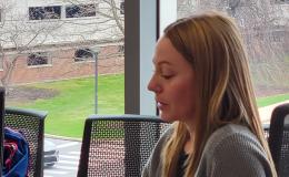 Linsday Wells, a woman with long blonde hair wearing a grey sweater, talks to the group.