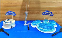 Two blue and white decorated cakes on a table with a blue tablecloth.