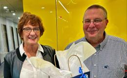 Betsy Beck and Joe Broniszewski stand at a table with their retirement gifts.