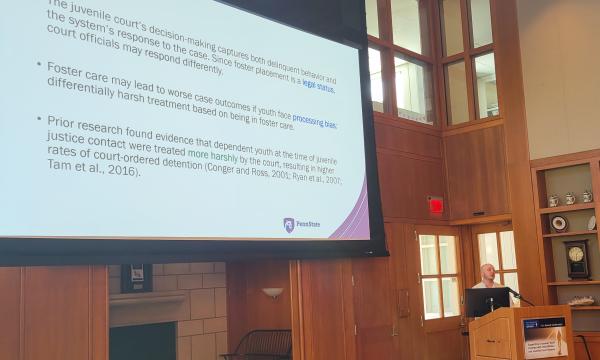 Ezra Goldstein stands at the podium to discuss if foster youth face harsher juvenile justice outcomes.